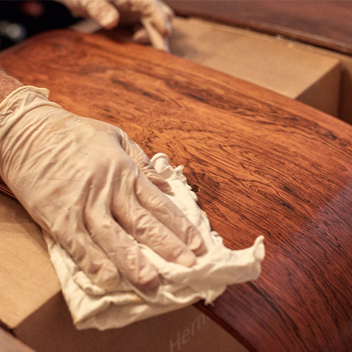 Close photograph of gloved hand polishing wood veneer
