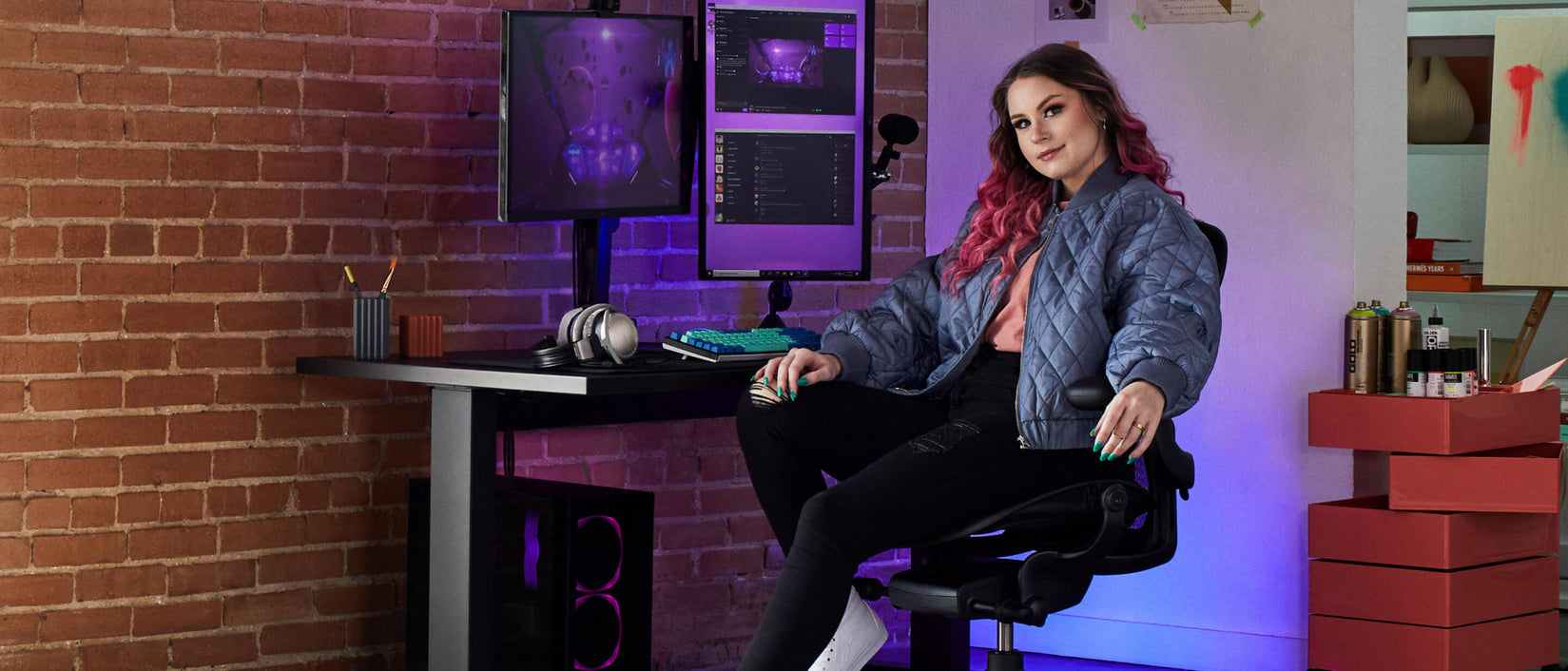 Photo of gamer Electra facing camera sat on Aeron gaming onyx black in front of Nevi gaming desk in black with Ollin monitor