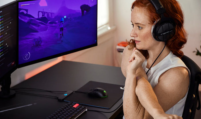 Photo of Dr Lindsey Migliore sat in a Embody gaming chair doing shoulder and back stretches in Embody gaming chair in cyan with Nevi gaming desk