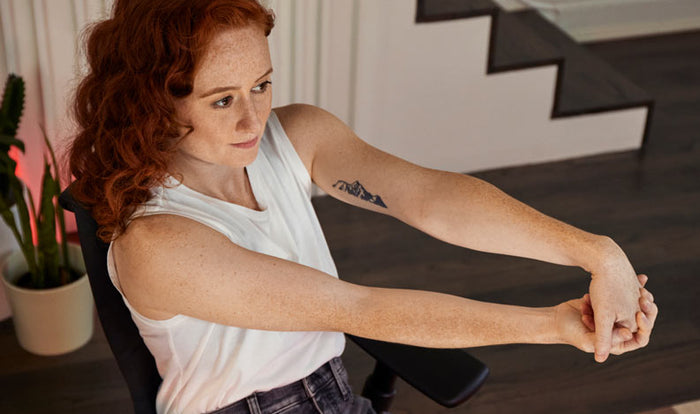Photo of Dr Lindsey Migliore sat in a Embody gaming chair doing a wrist extensor stretch in Embody gaming chair