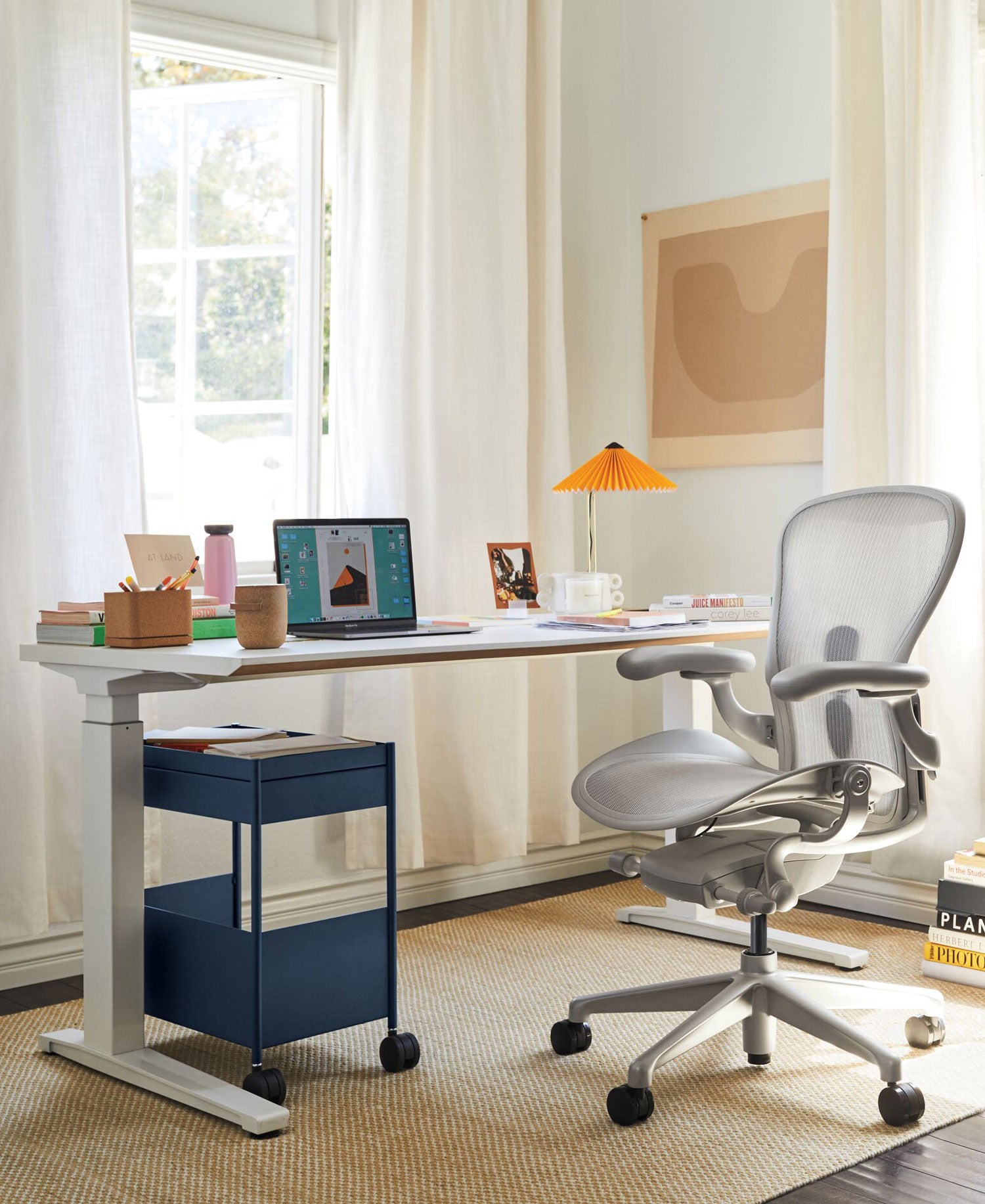 Home Office with Aeron office chair in mineral white, with Jarvis sit stand desk in white accessories include Oripura laptop stand and Hay Matin table lamp