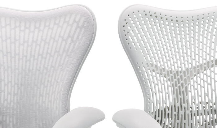 Two white Mirra 2 office chairs by Herman Miller, positioned side by side. Showcasing the two back options, one with an additional layer of fabric and one without.