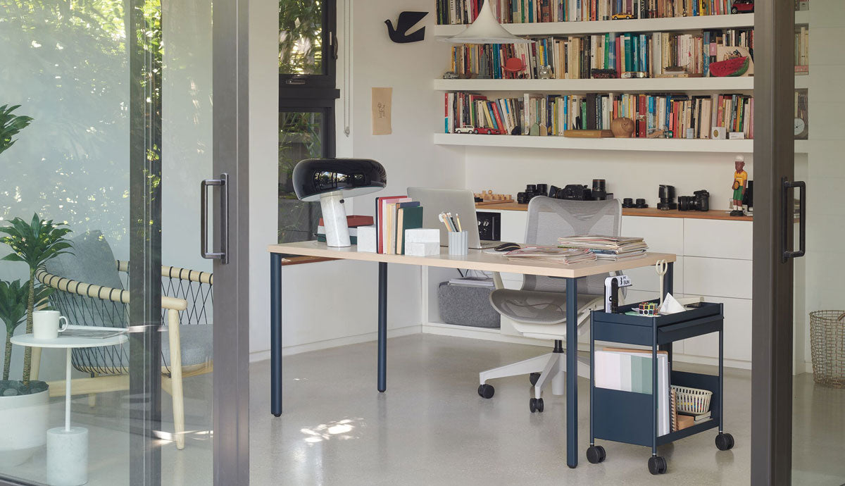 A bright, modern home office featuring a Herman Miller OE1 desk, a blue OE1 office trolley and a Cosm ergonomic chair.