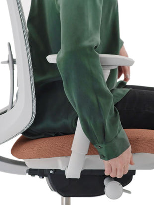 Side view of a pink and grey Verus office chair by Herman Miller, showing the adjustable seat depth feature.