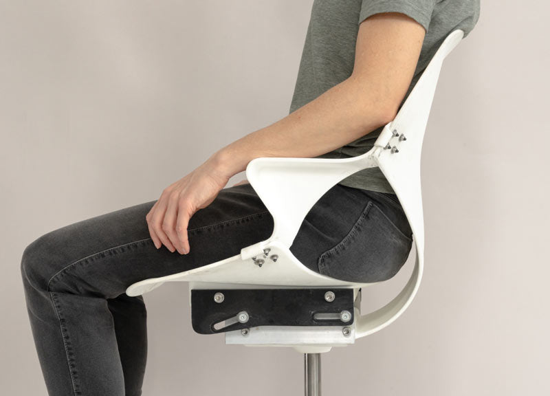 Side of view of person sat in Zeph office chair in unfinished state showing the flexibility of the seat back element of chair