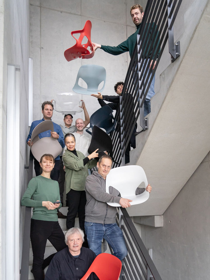 Photograph of members of the Studio 7.5 design team in a stair well with come holding various parts of the Herman Zeph chair that they designed