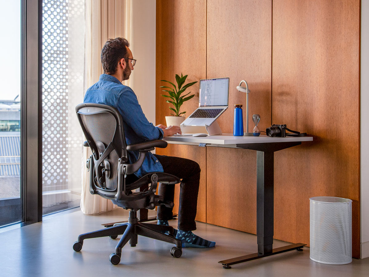 Photo of man sat in Aeron office chair in graphite correctly showing that feet should be on floor if sitting properly