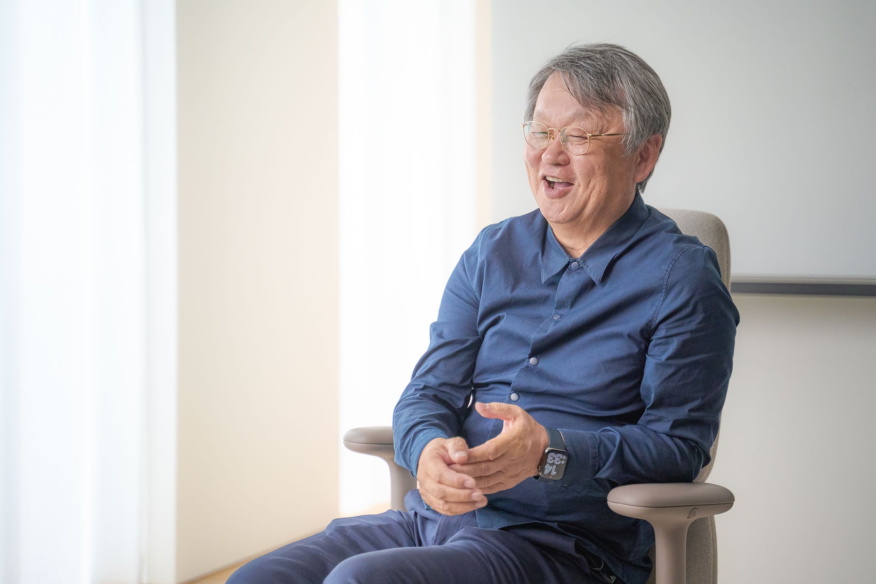 Cheerful photograph of of Naoto Fukasawa sat in an Asari office chair