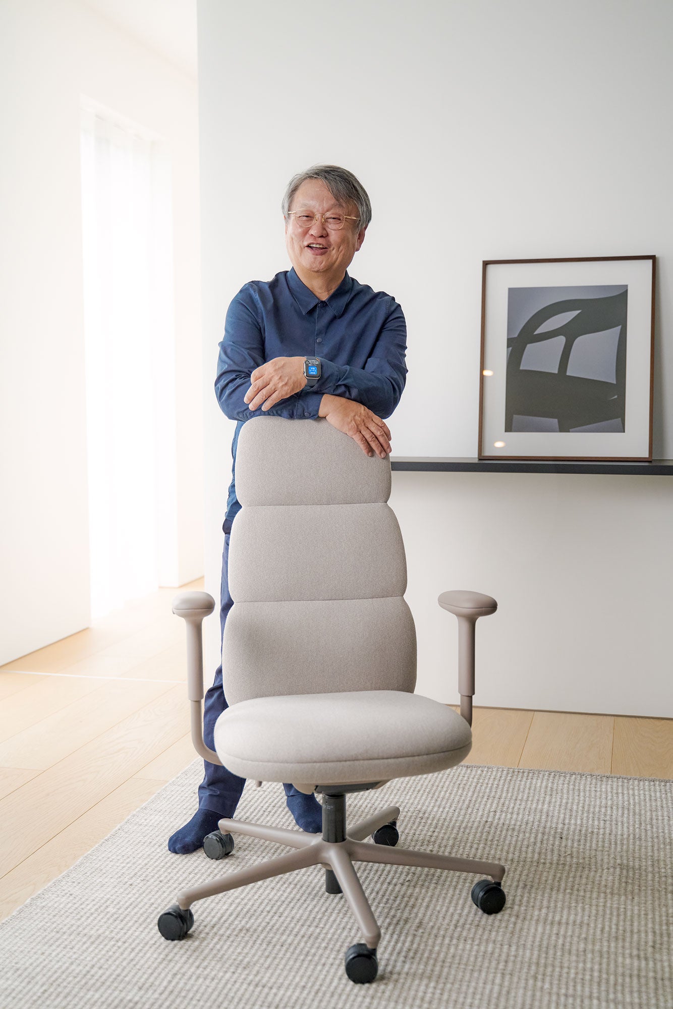 Photograph of Naoto Fukasawa stood behind an Asari home office chair in alpine white