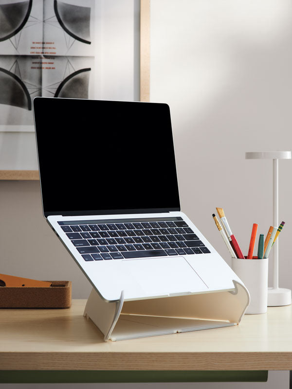 Close up of laptop on a white oripura stand on home office desk and white desk lamp