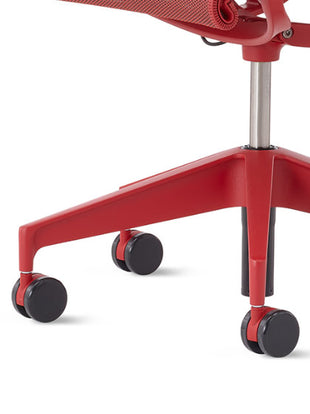Close-up of a red Setu office chair by Herman Miller, showing the black multi-purpose castors.