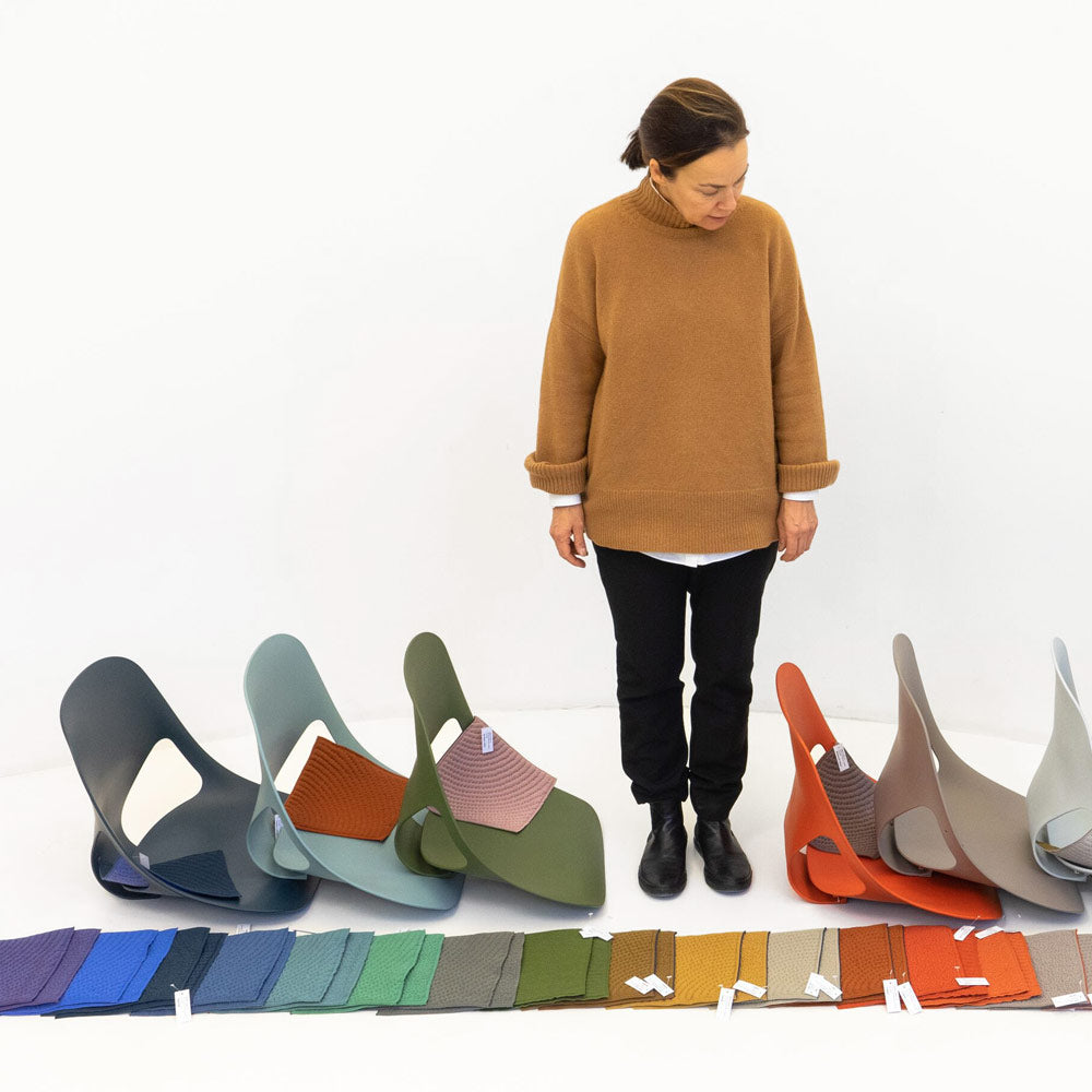 Designer from Studio 7.5 looking down to floor at materials swatches and Zeph seats in a variety of colours