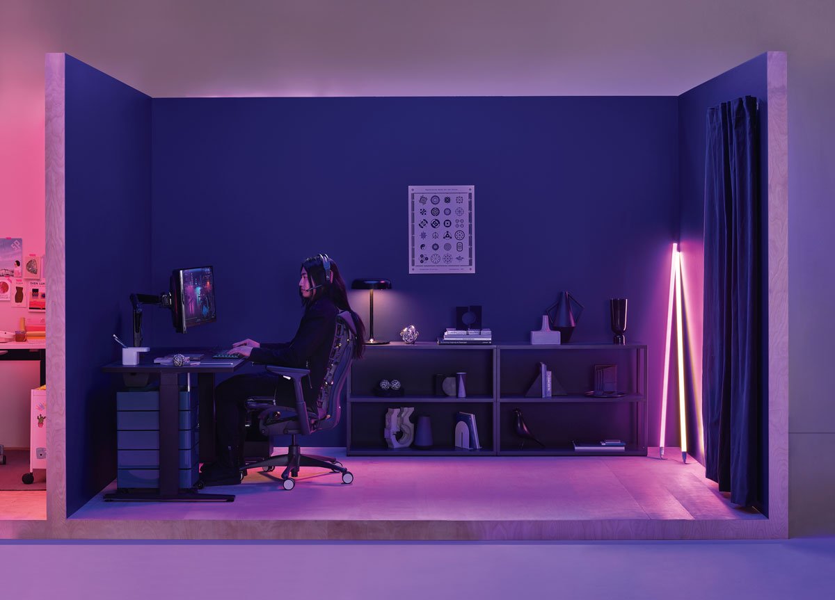 Gaming set up office with lady playing sat in Logitech Embody gaming chair in black with Nevi gaming desk in black with Hay neon tube lighting in the corner