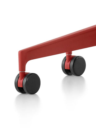 Close-up of a red Cosm office chair by Herman Miller, showing the black multi-purpose castors.