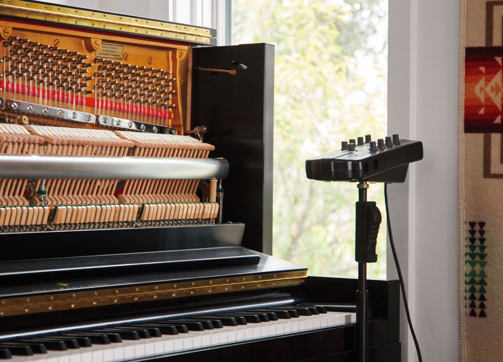 Photo of upright piano with front open with sound recording equipment  next to it