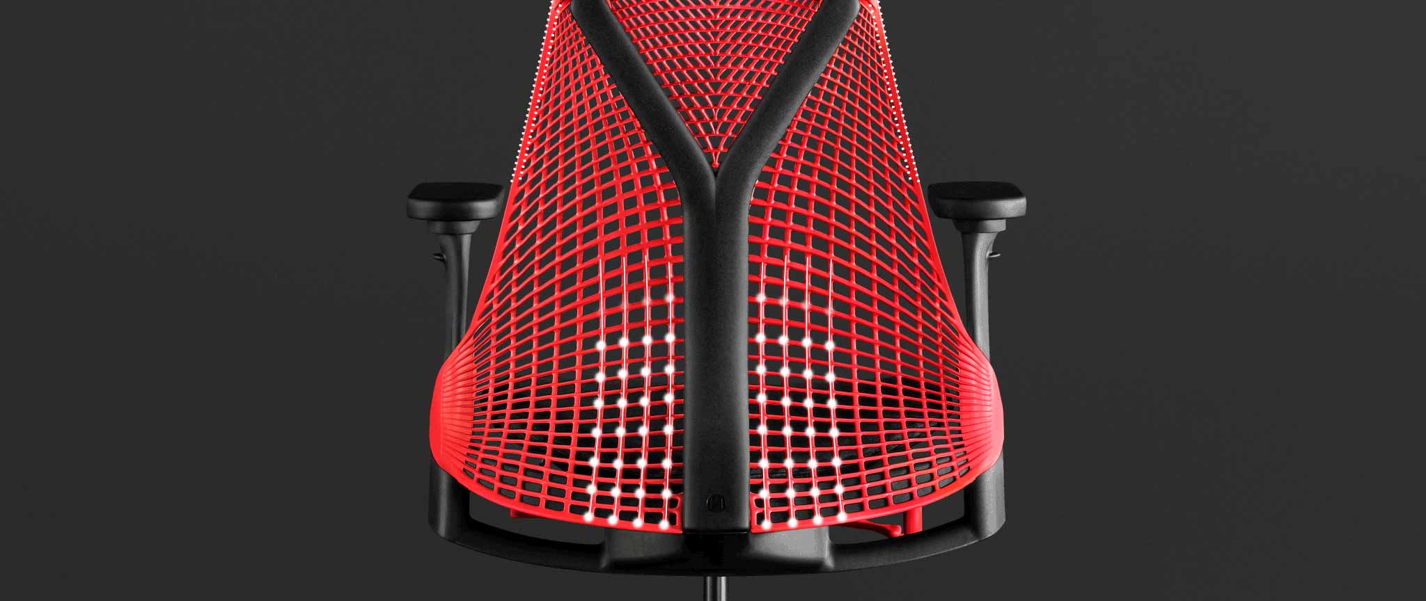 Rear view of a red and black Sayl gaming chair by Herman Miller, overlaid with white graphics highlighting the suspension back.