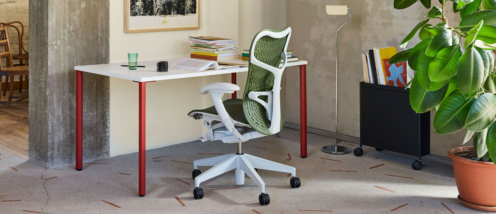 A warm home office featuring a green Mirra 2 office chair and white and red OE1 desk by Herman Miller.