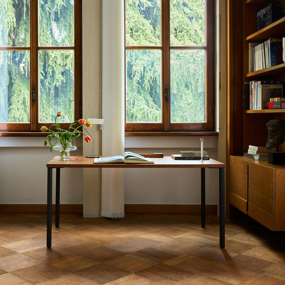 A Herman Miller OE1 desk with a walnut top and navy blue legs. Featuring a cream HAY Apex lamp.