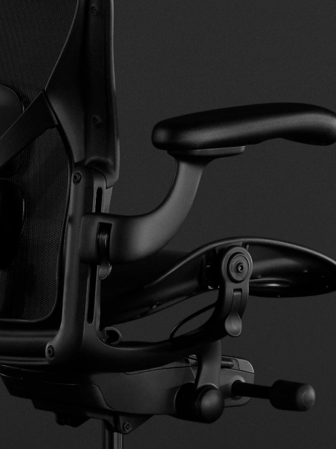 Side view of a black Aeron gaming chair by Herman Miller, showing the tilt feature.