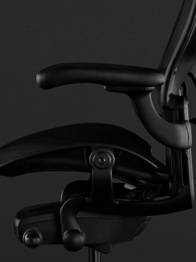 Side view of a black Aeron gaming chair by Herman Miller, showing the fully adjustable arms.