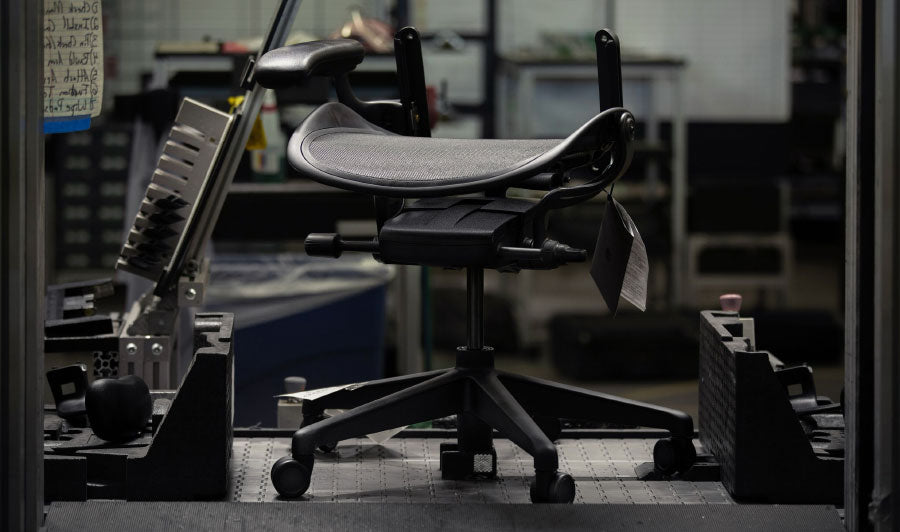 Base and seat of black Aeron gaming chair by Herman Miller in a factory setting.
