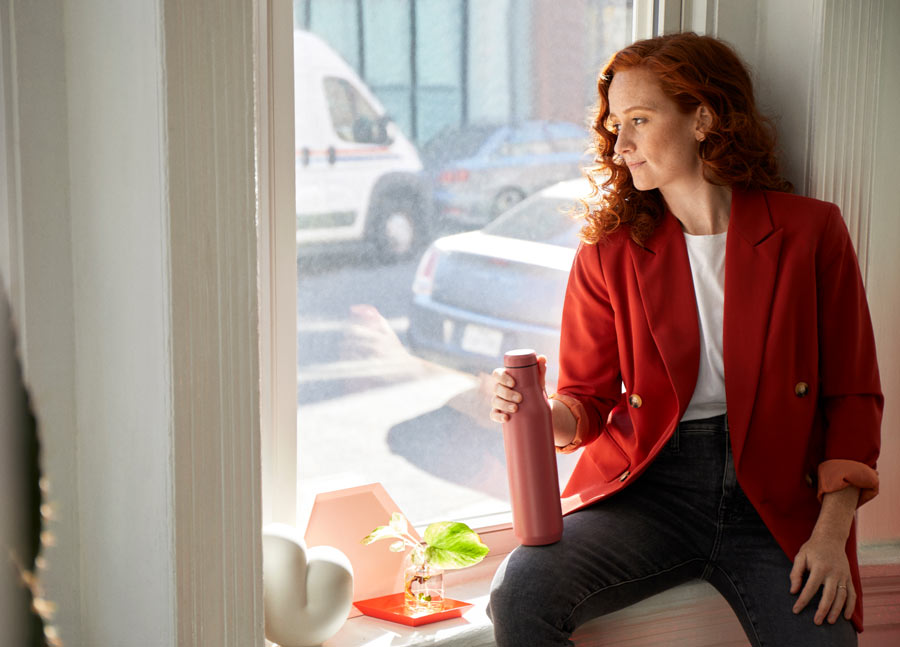 Photo of Dr Lindsey Migliore taking a break sat on windowsill looking out window