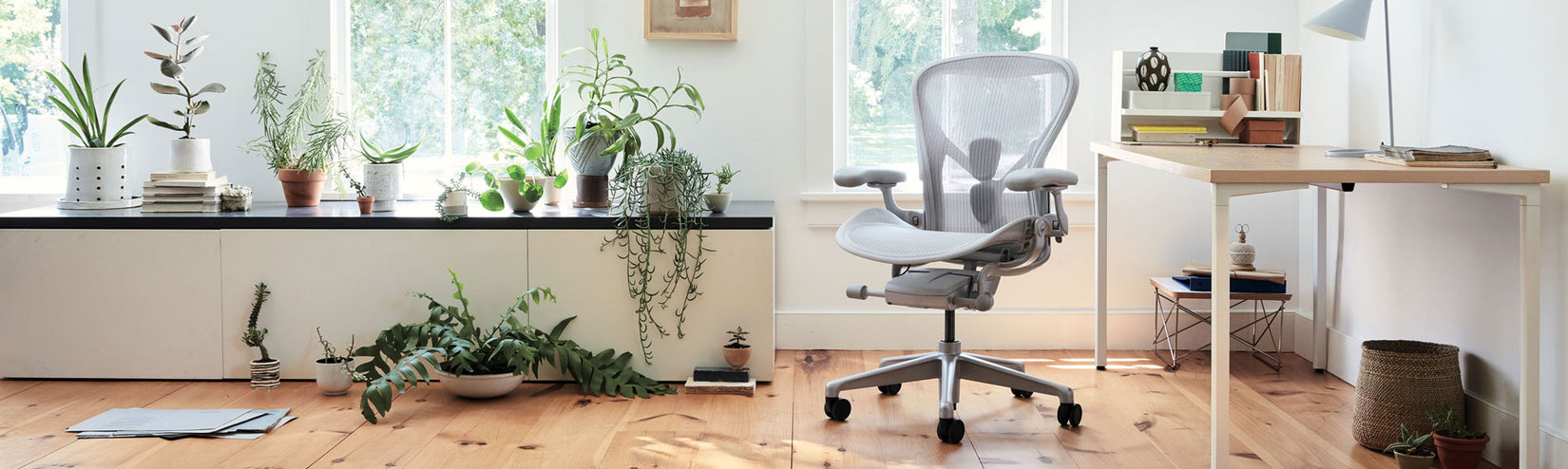 Herman Miller Aeron in mineral with OE1 fixed height desk with white frame and ash top in a bright plant filled home office setting