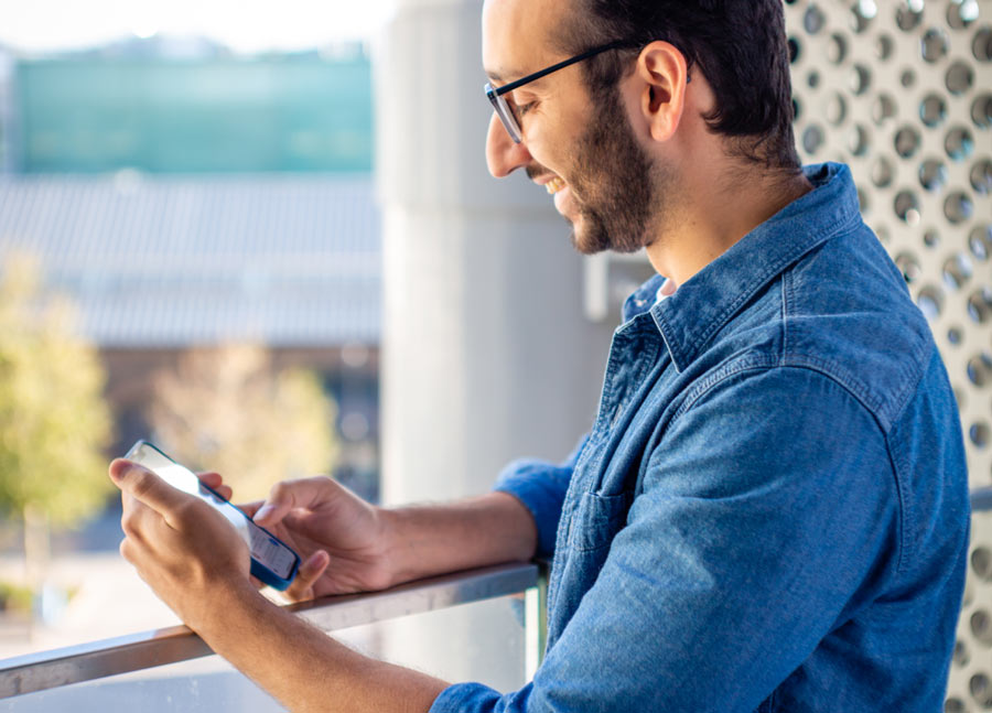 Photo of Ali Abdaal at window in his home looking at his phone