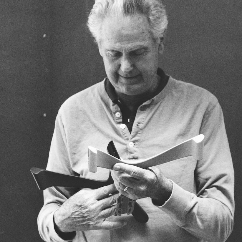 Black and white photograph of Don Chadwick holding chair components