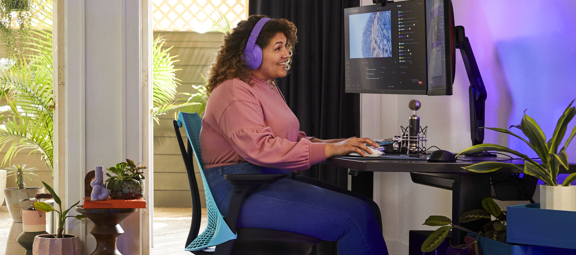 Photo of Friskk sat gaming on Sayl in black and ocean deep blue with Nevi gaing desk in black