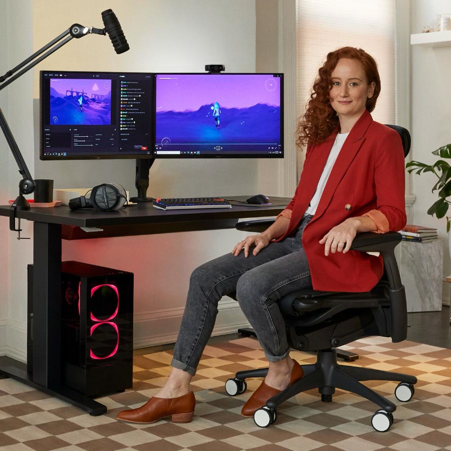 Esports doctor Lindsey Migliore in front of Gaming set up with dual monitors on Ollin monitor arms