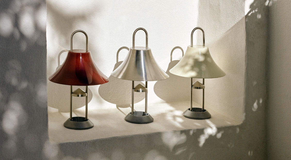 Three HAY Mousqueton portable lamps in red, silver and white, positioned in a white wall alcove.