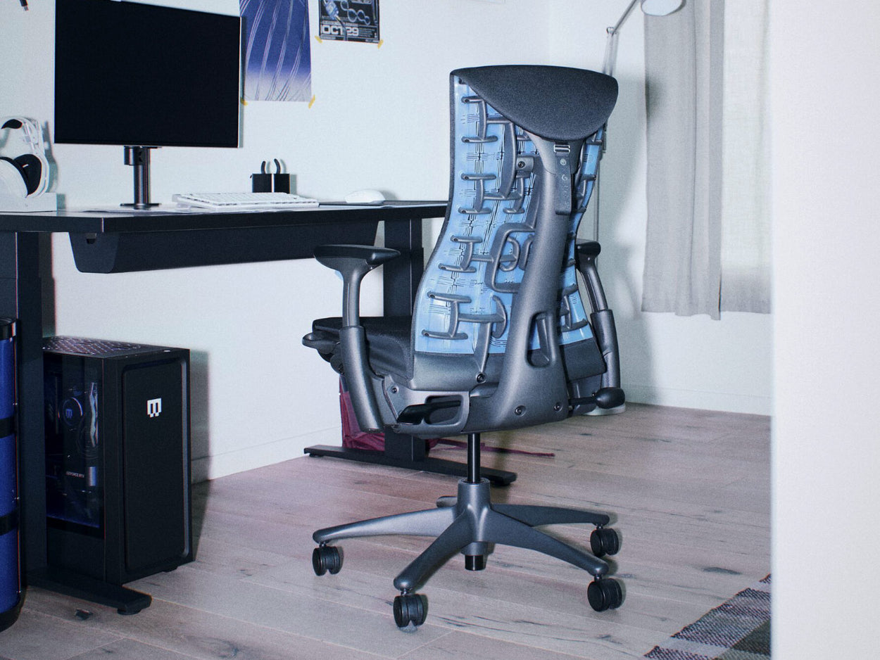 A black and cyan blue Herman Miller Embody ergonomic gaming chair as part of a PC gaming setup alongside a black Nevi Desk