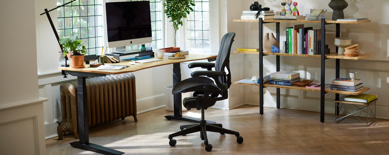 Home office showing Iconic Herman Miller Aeron chair in onyx black with sit-stand Jarvis desk with legs and contoured Bamboo top.
