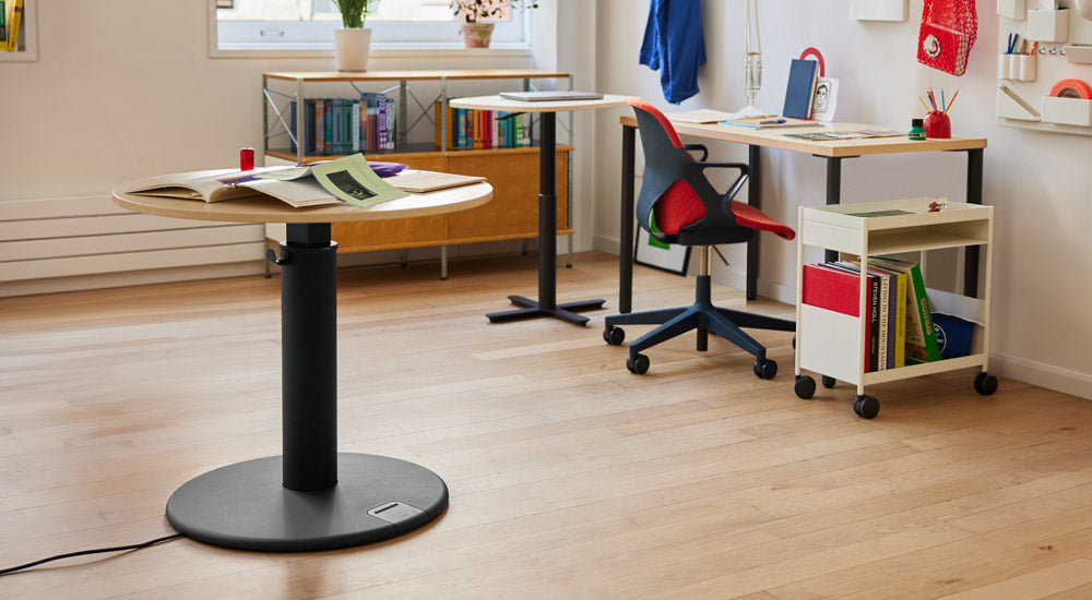 A colourful home office featuring a black and ash OE1 standing desk by Herman Miller, a Passport work table, an OE1 desk, a black and red Zeph chair and a white OE1 trolley.