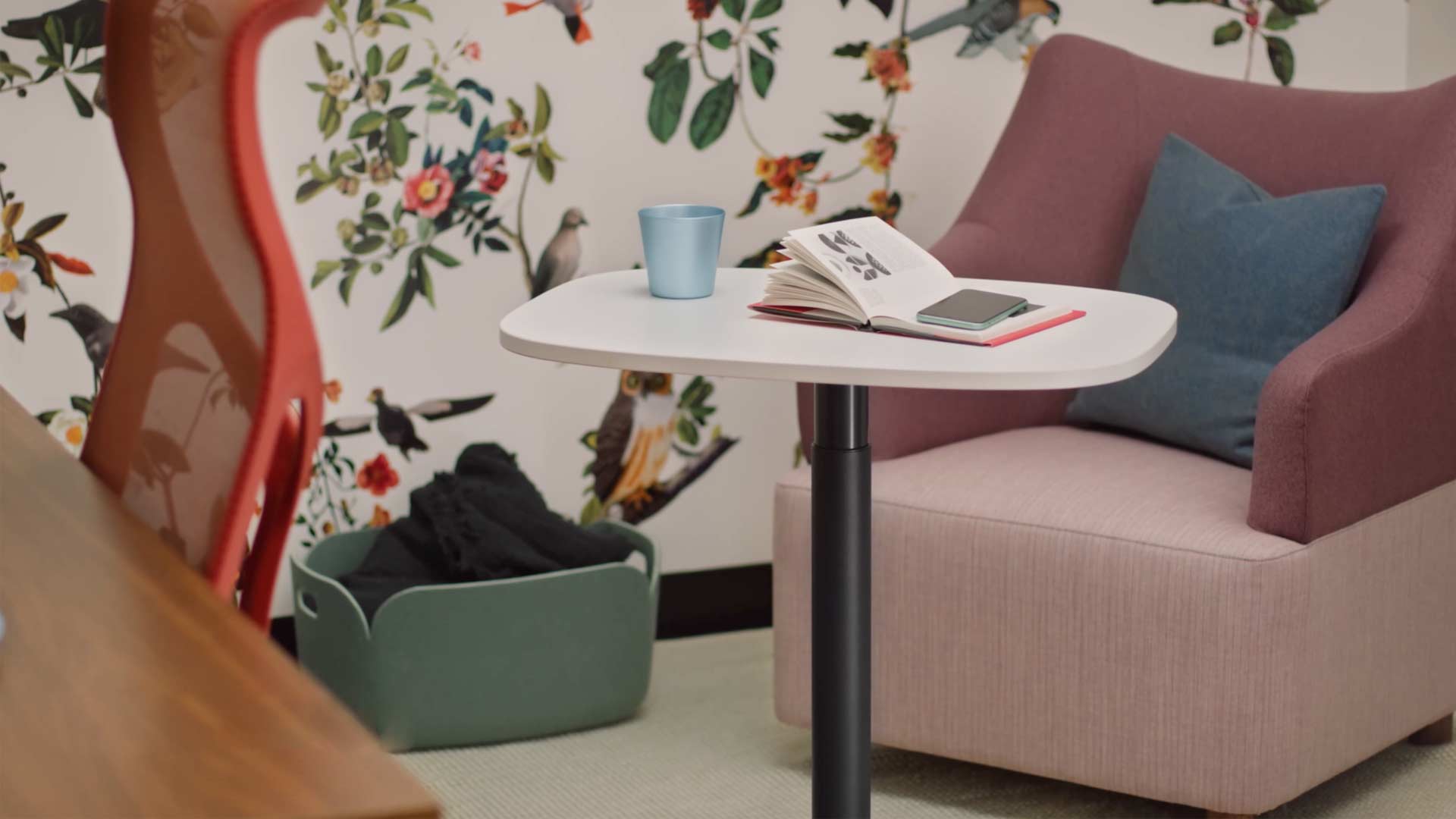 A video of a women sitting in a yellow Wilkes armchair using a Passport table by Herman Miller. The video continues to show the Passport table being used in a number of locations, including both offices and home environments.