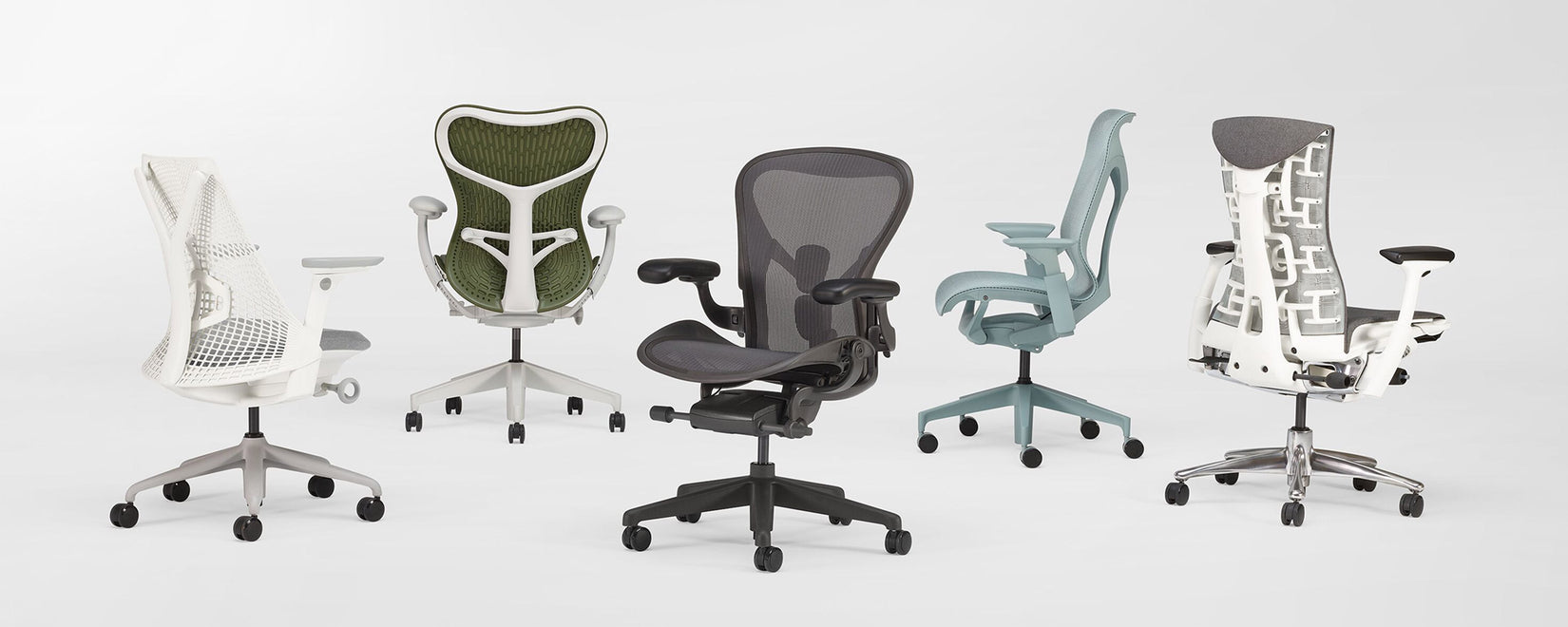 Lineup of 5 Herman Miller ergonomic office chairs in a white studio. Featuring Sayl, Mirra 2, Aeron, Cosm and Embody.