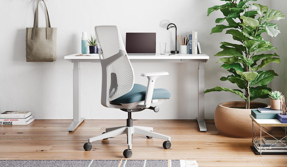 A white and blue Verus office chair by Herman Miller, positioned in front of a white Nevi standing desk.