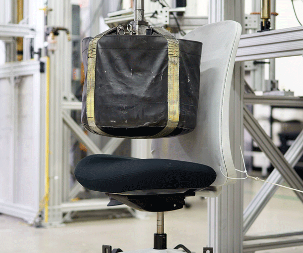Photo of drop test, showing weight being dropped onto chair seat pad that all Herman Miller chairs go through.
