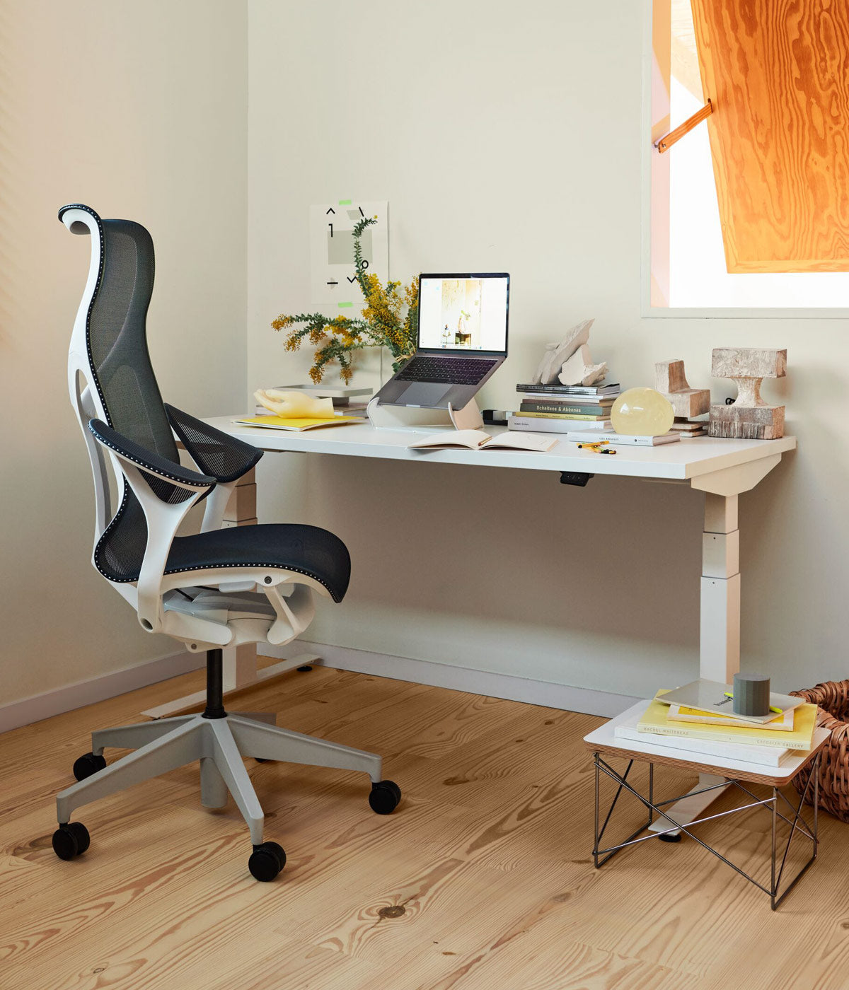 A Herman Miller Cosm Desk Chair in white and blue with an all white Nevi Sit Stand Desk