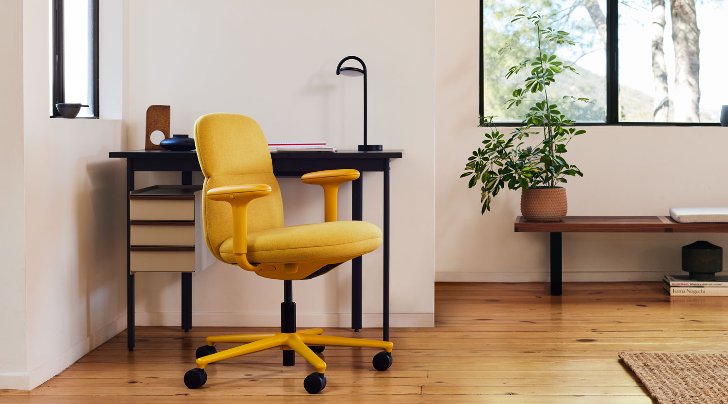 A yellow Asari mid back office chair in front of a black and sandstone Mode desk with a black Marselis table lamp.
