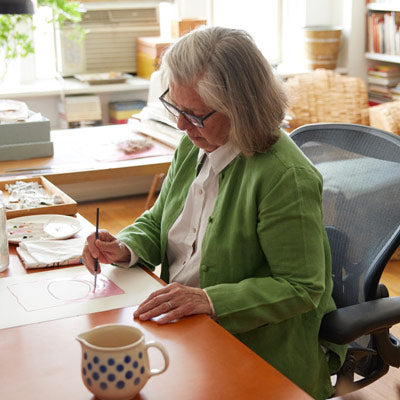 Illustrator, painter and author sat painting in a Herman Miller Aeron office chair in graphite