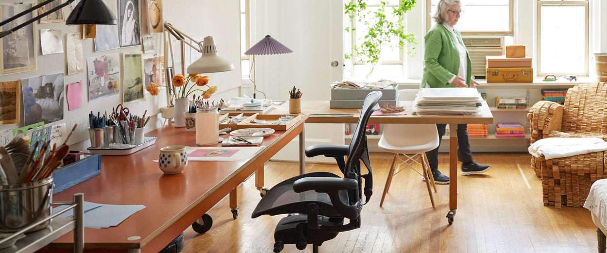 Photo of Maira Kalman's artist studio containing Aeron office chair in graphite and Hay Matin table lamp