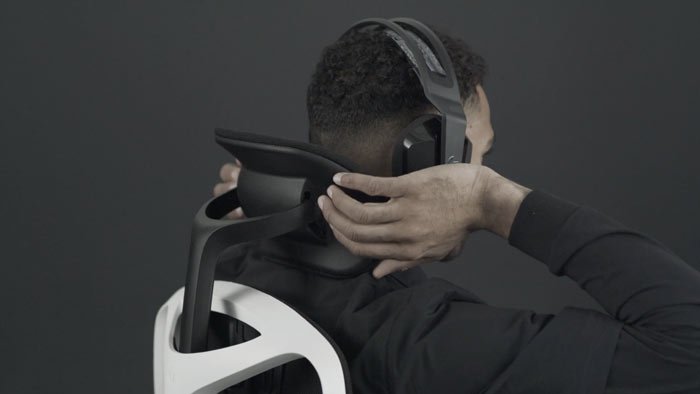 A video of a person sitting in a white and black Vantum gaming chair by Herman Miller, reaching behind the chair to adjust the headrest.