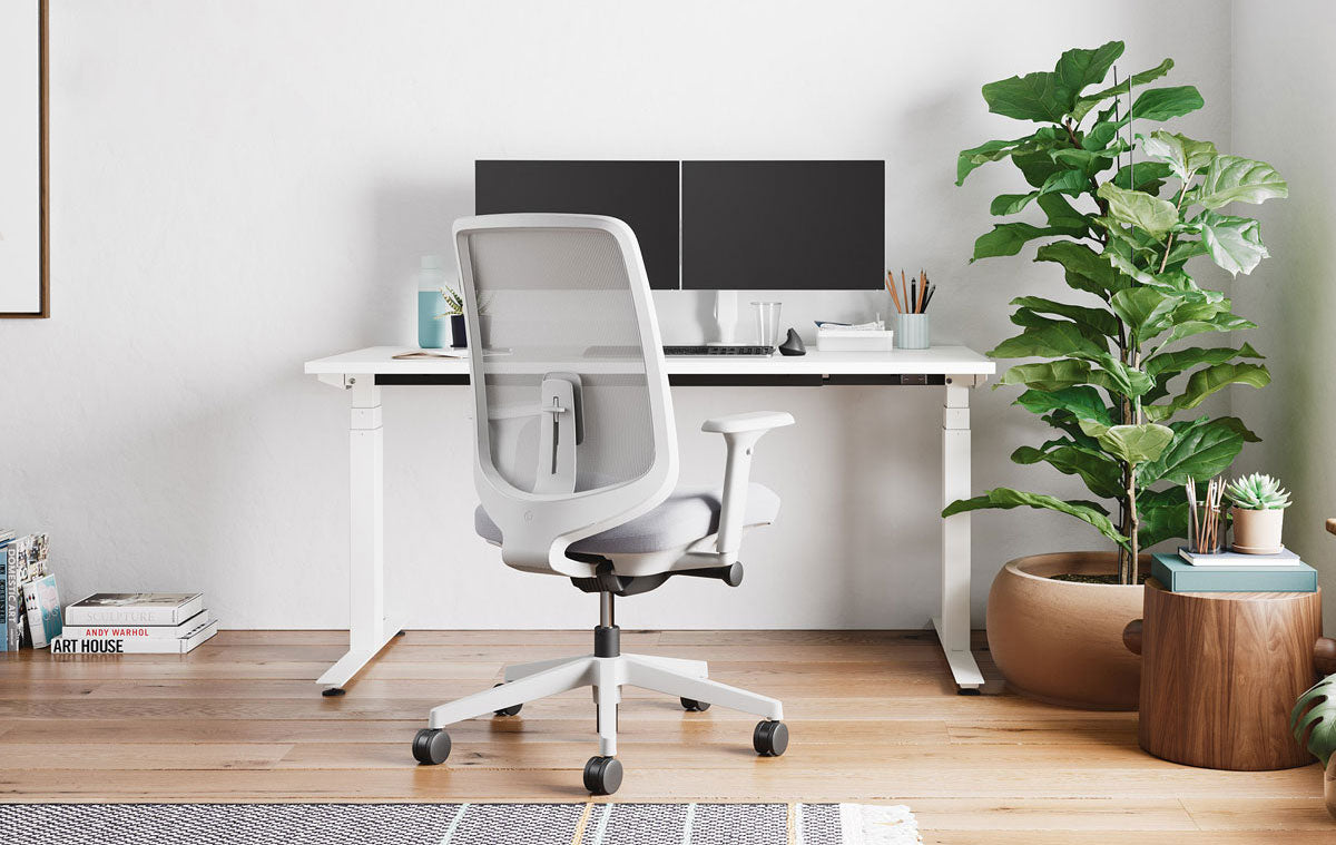 Home office with Verus office chair in mineral white with pale grey seat pad, infront of Nevi sit-stand desk in white with dual screens on monitor arms