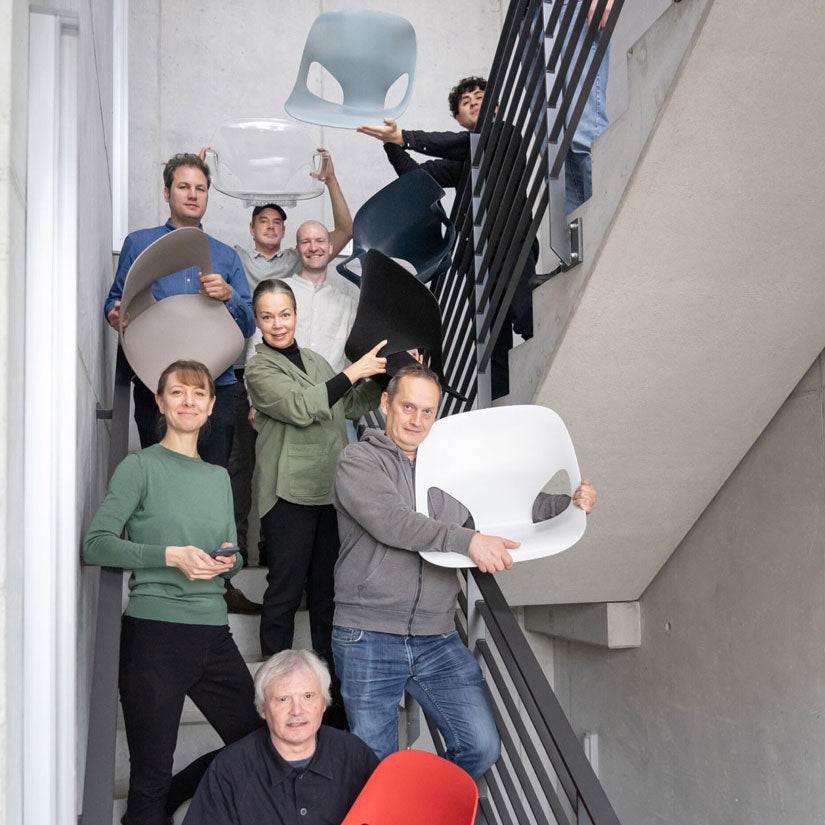 Photograph of members of the Studio 7.5 design team in a stair well with come holding various parts of the Herman Zeph chair that they designed