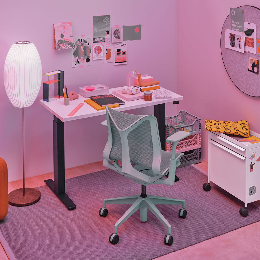 Home office setting featuring low back Cosm office chair in glacier grey in front of Nevi sit-stand desk with black legs and white top