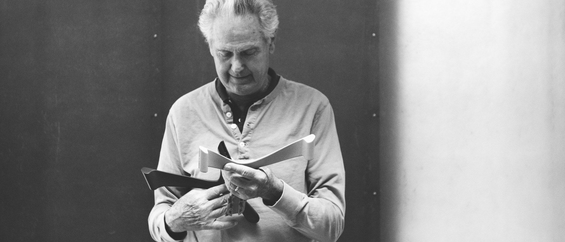 Black and white photograph of Don Chadwick holding chair components